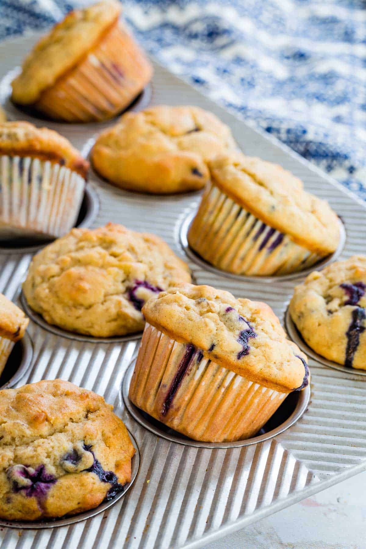 A 12-count muffin tin with a batch of blueberry banana muffins in it