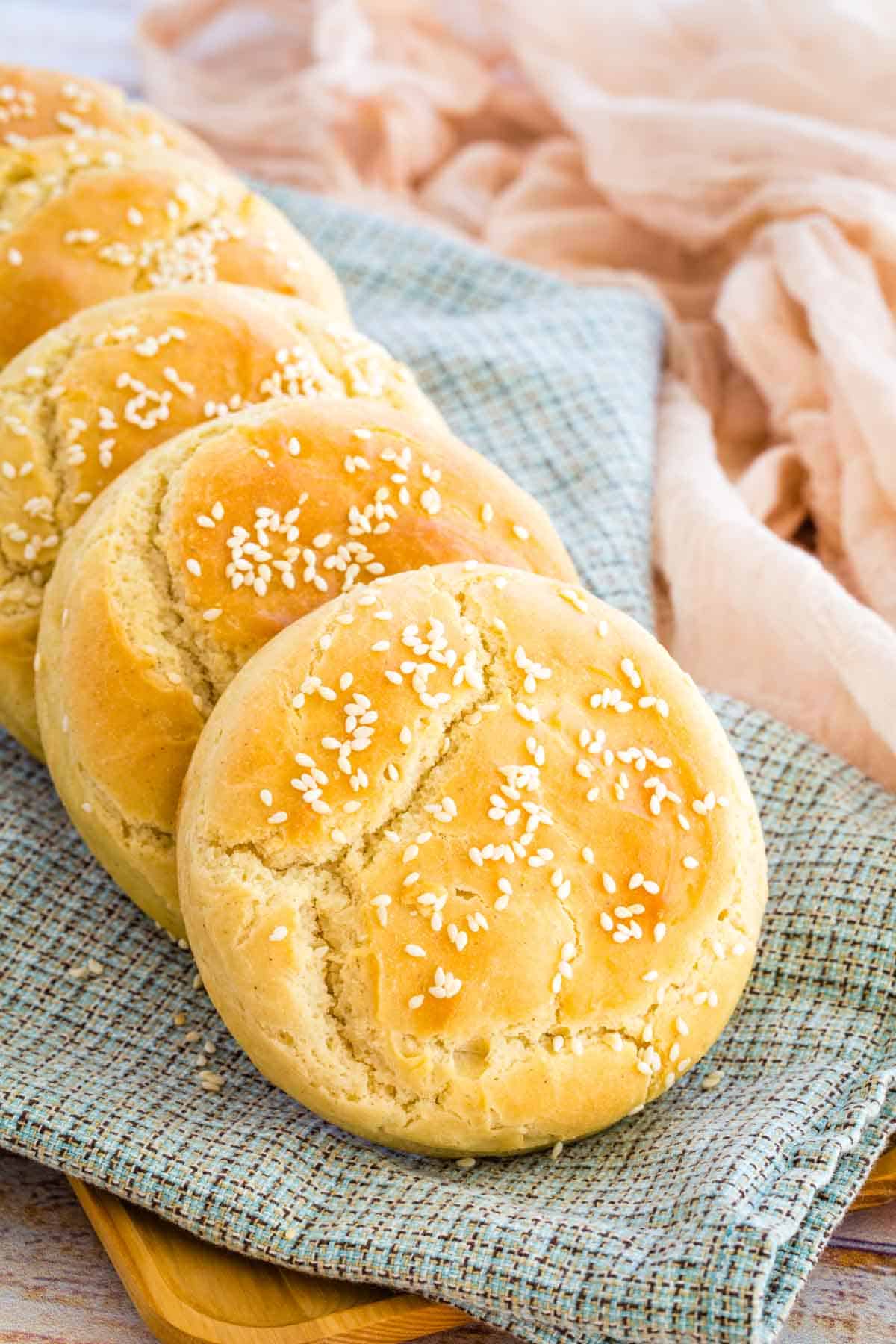 A row of hamburger buns arranged on a cloth.