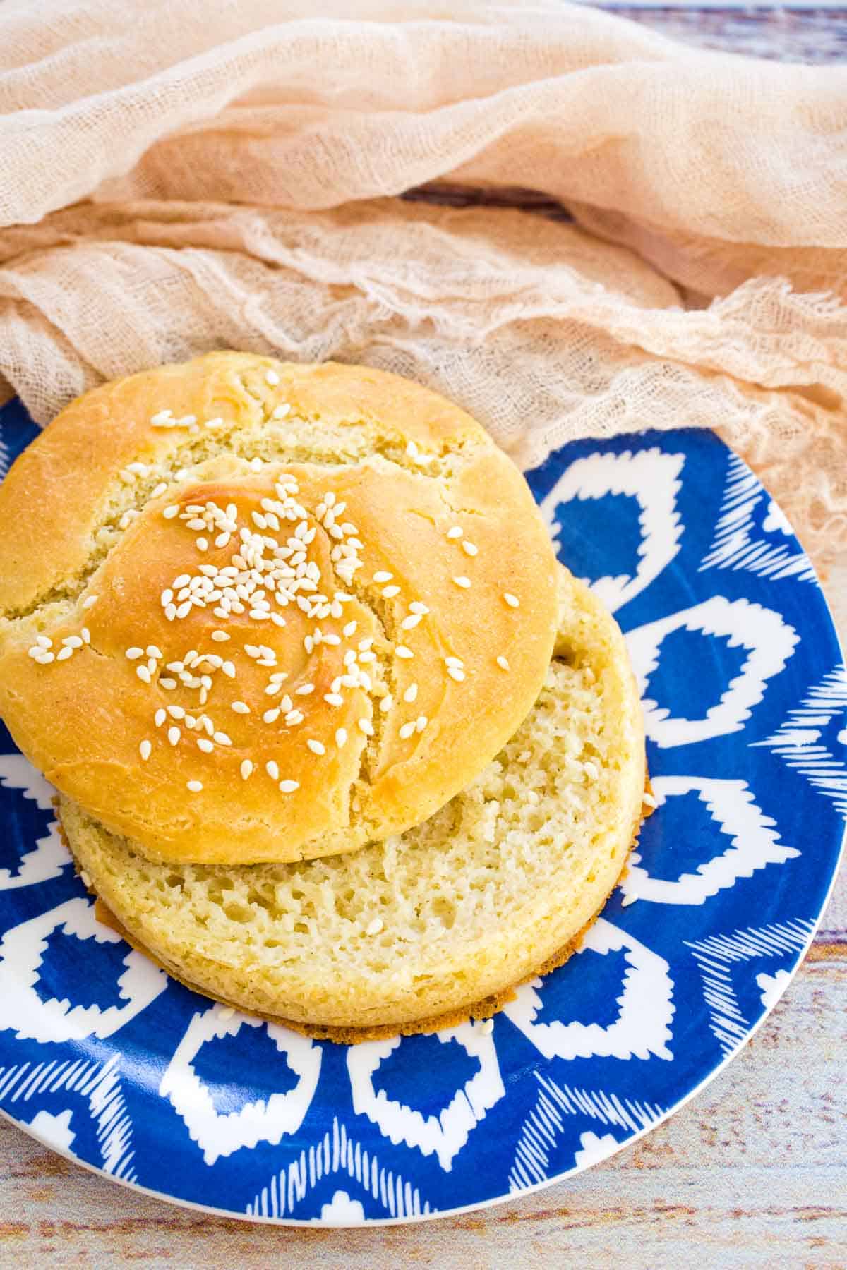 A gluten free hamburger bun sliced open on a plate.