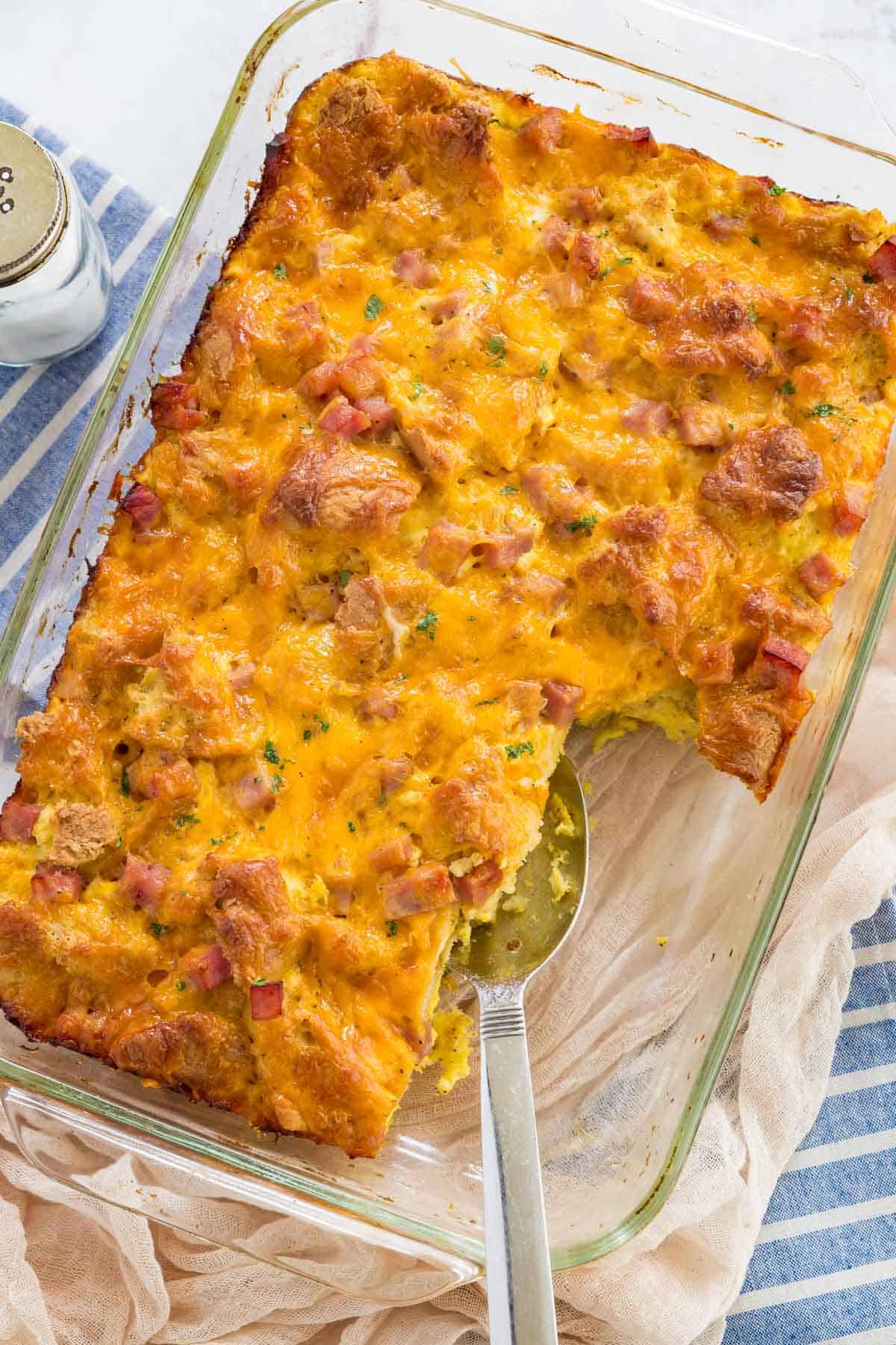 Top view of a gluten free ham and cheese breakfast casserole in a clear baking dish with slices missing.