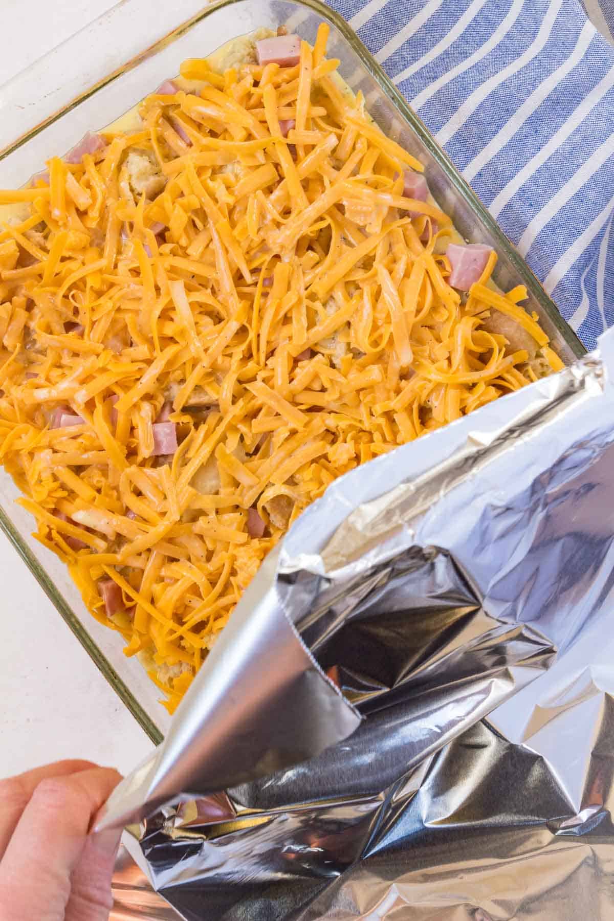 Foil is placed over an unbaked gluten free ham and cheese strata.