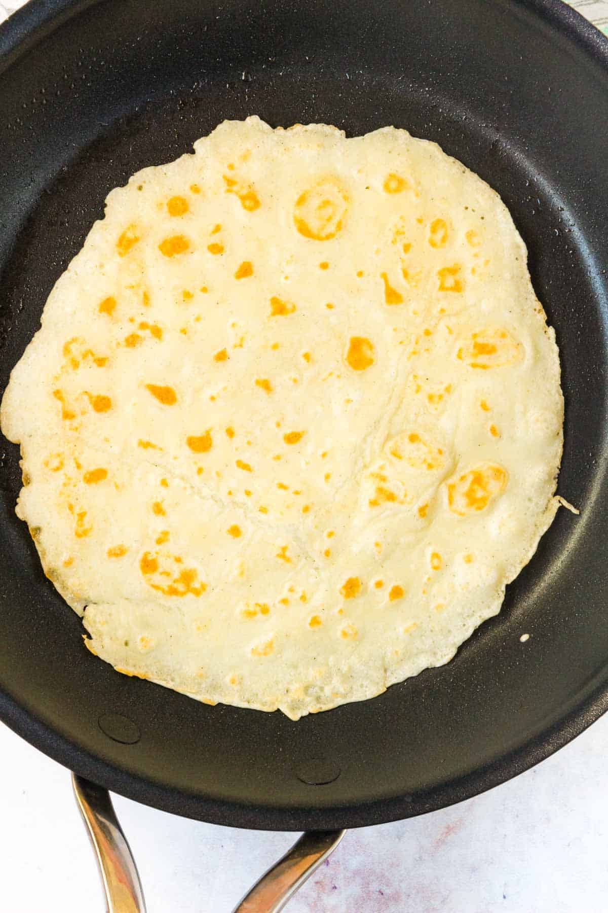 A crepe that's been flipped in a skillet to cook on the opposite side.