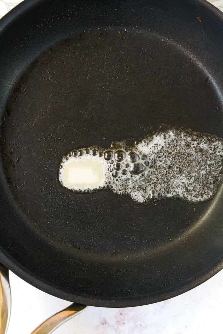 A slab of butter melts in a hot skillet.