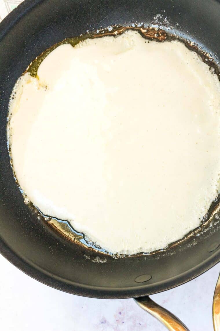 Crepe batter swirled into a thin circle in a skillet.