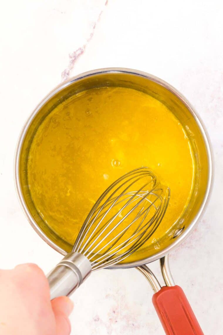 Egg yolks are whisked together with lemon juice in a saucepan.