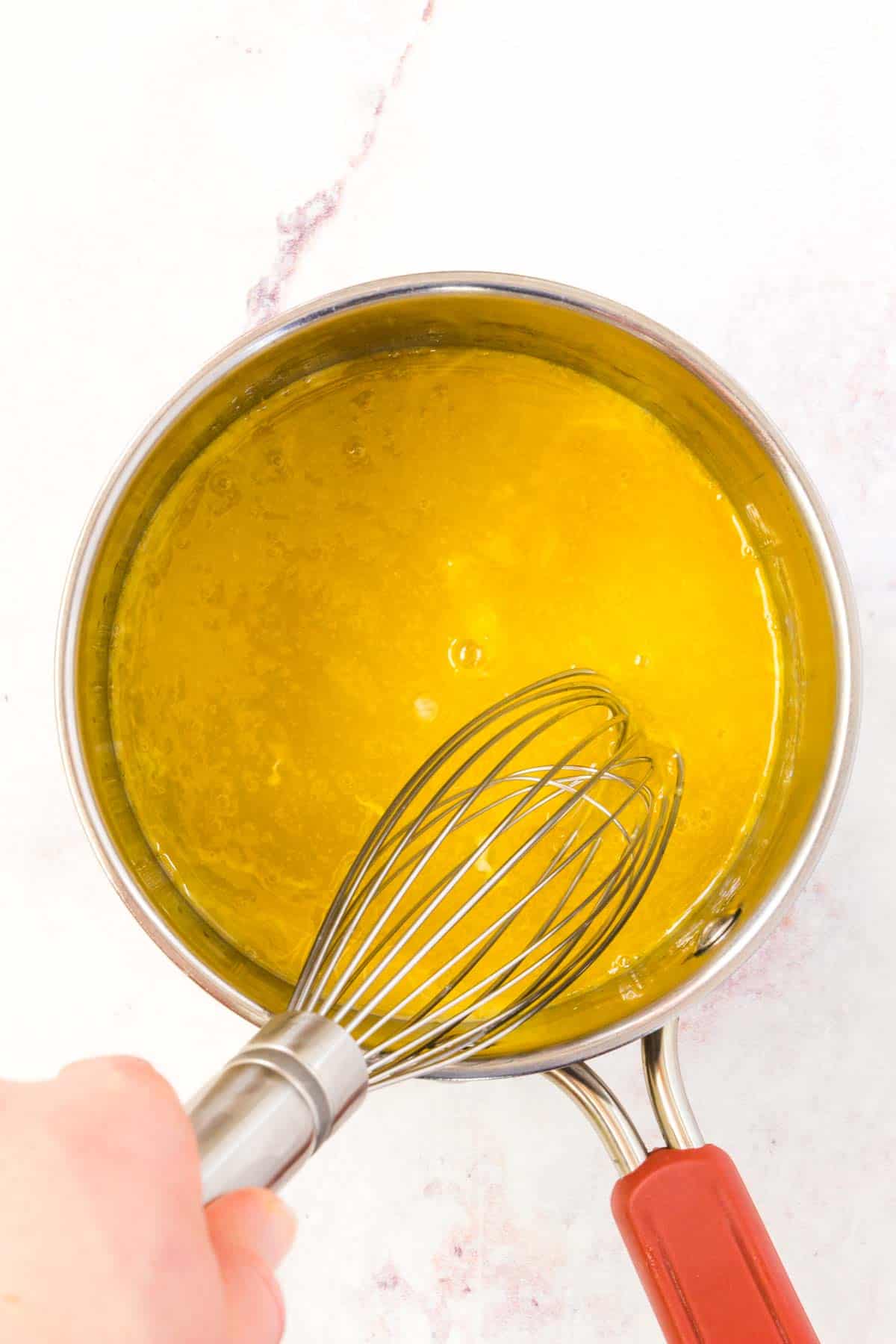 Egg yolks are whisked together with lemon juice in a saucepan.