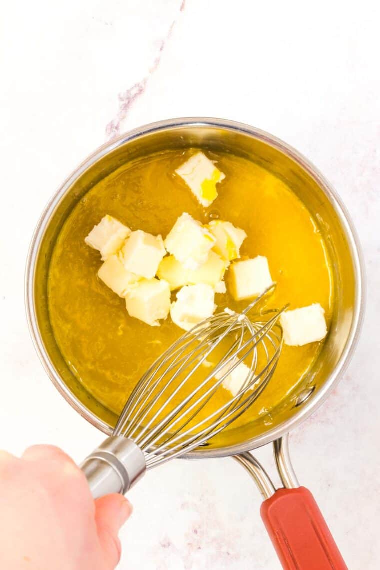 Cubes of butter are added into a saucepan with egg yolks and lemon juice.