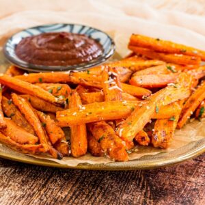 A plate of roasted carrot fries sprinkled with parmesan and parsley.