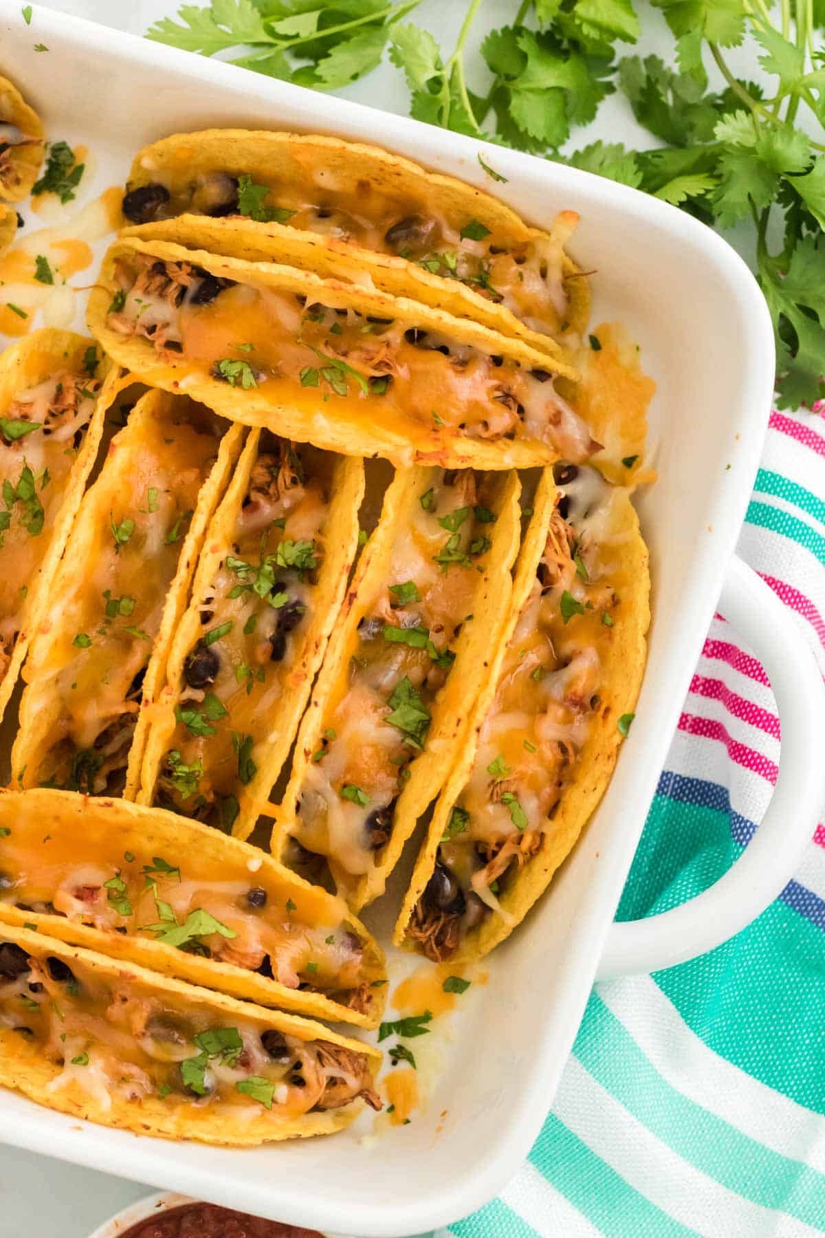 Top view of baked chicken tacos in a white baking dish.