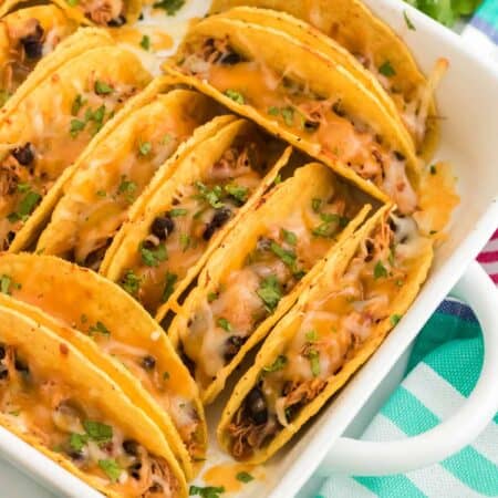 Top view of baked chicken tacos in a white baking dish.