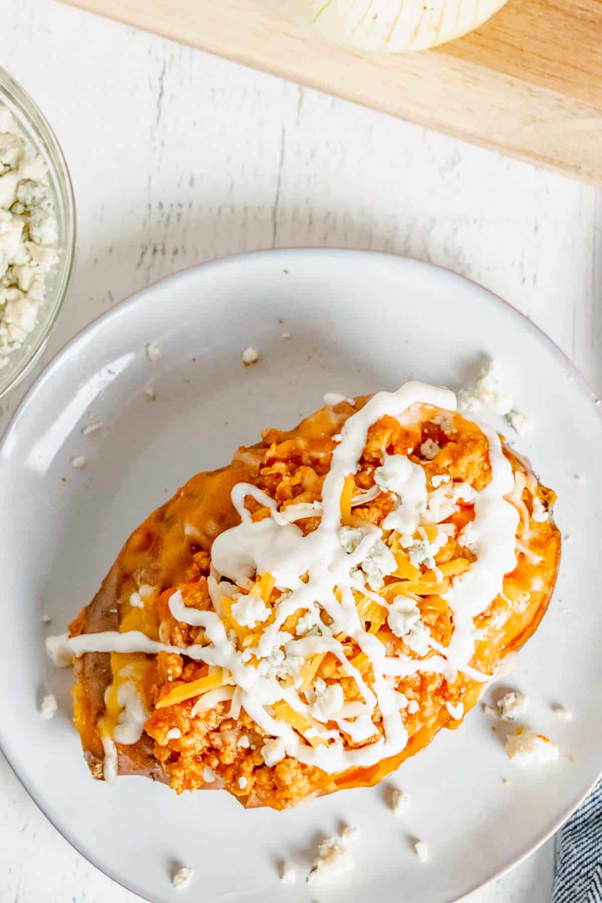 A baked sweet potato stuffed with cheese and buffalo chicken and topped with blue cheese crumbles and a drizzle of Ranch dressing.