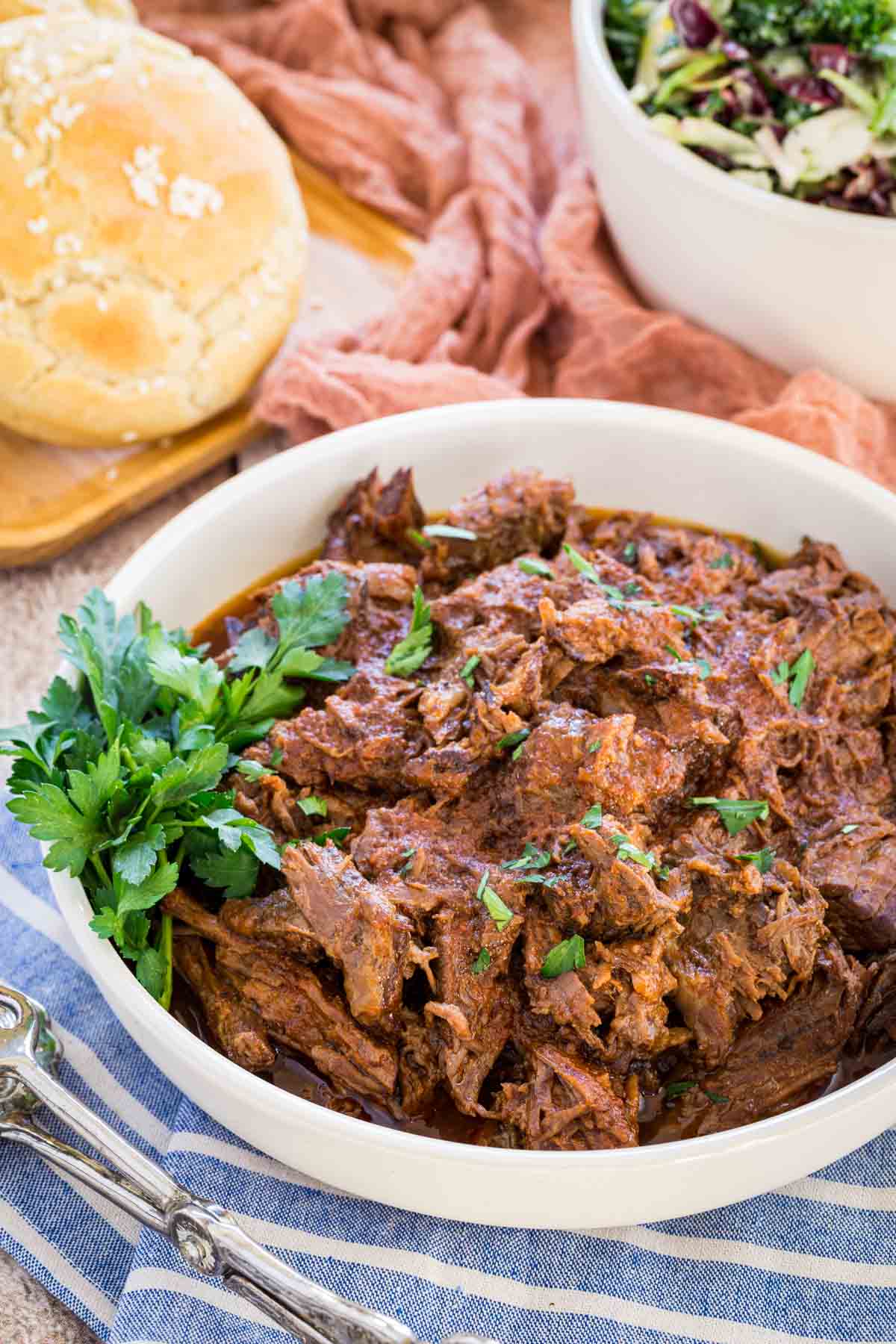 A bowl of Crockpot barbecue beef next to gluten-free buns.