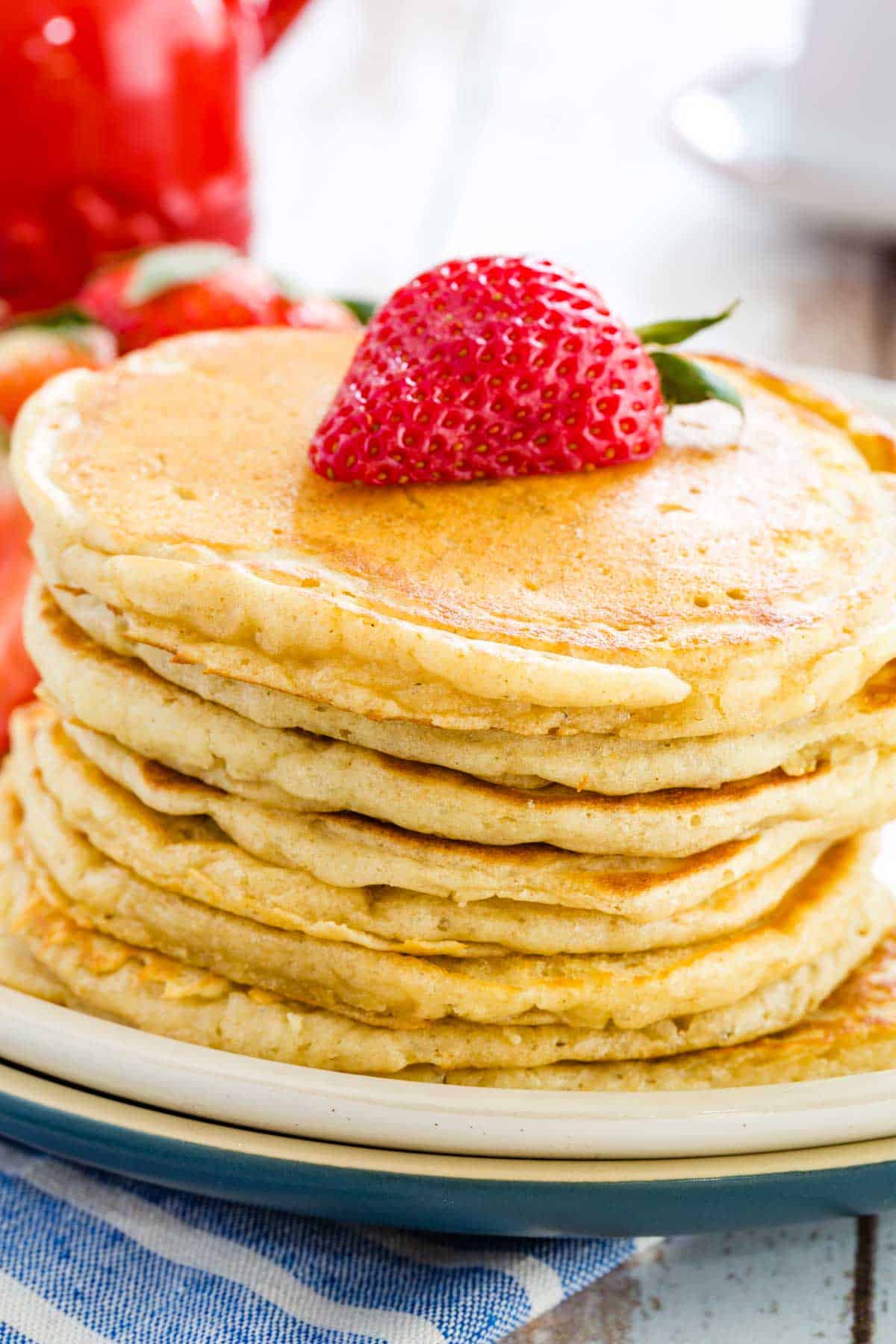 A stack of gluten free buttermilk pancakes topped with half a strawberry.