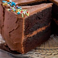 A slice of gluten-free chocolate layer cake being served from the full cake.