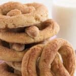 A soft pretzel with cinnamon sugar leaning against a stack of more pretzels.