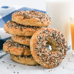 A stack of everything bagels with one leaning against the stack.