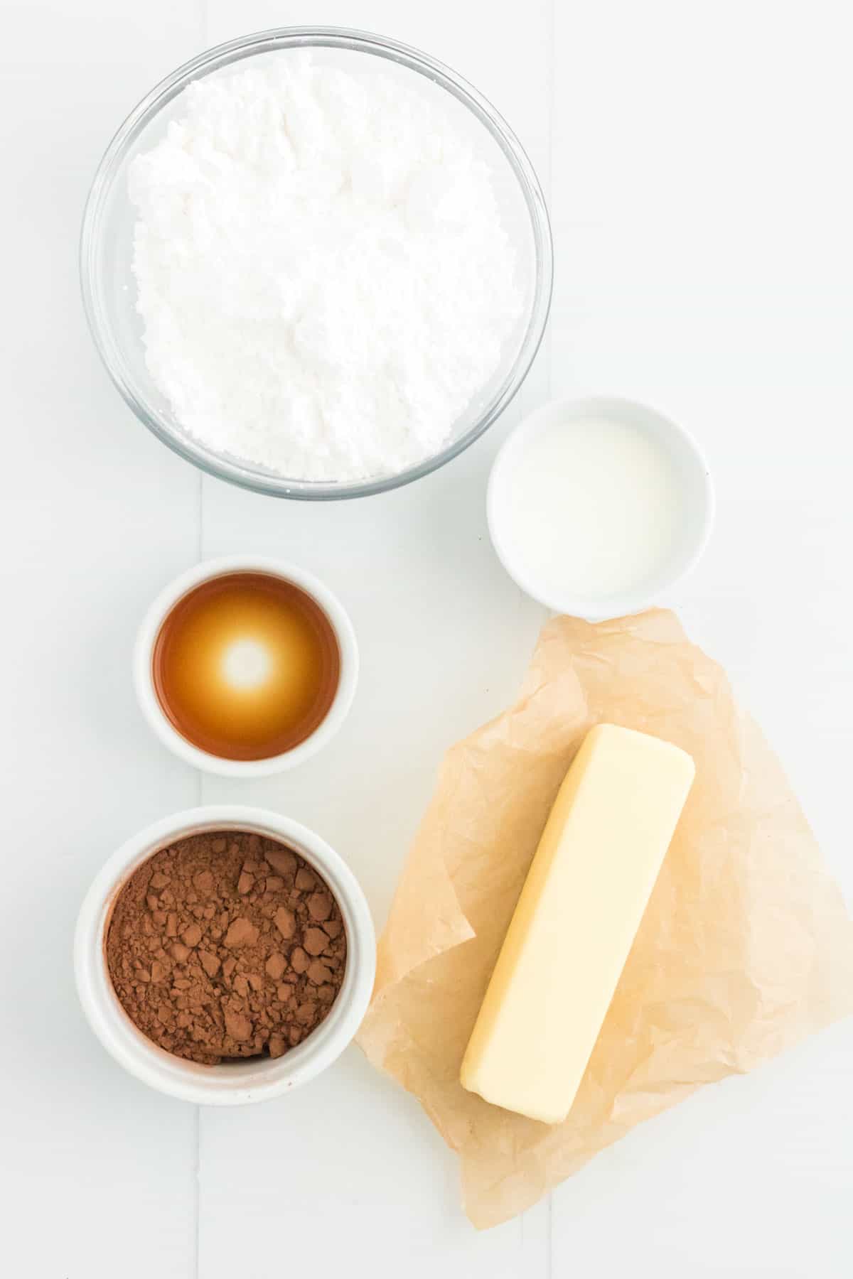 A stick of butter and bowls of ingredients for making the chocolate frosting.