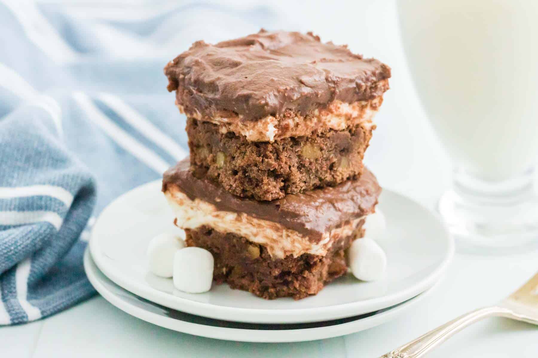Two stacked gluten free rocky road brownies on a couple of white plates.