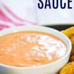 A white bowl of bang bang sauce on a dish with a breaded food around it.