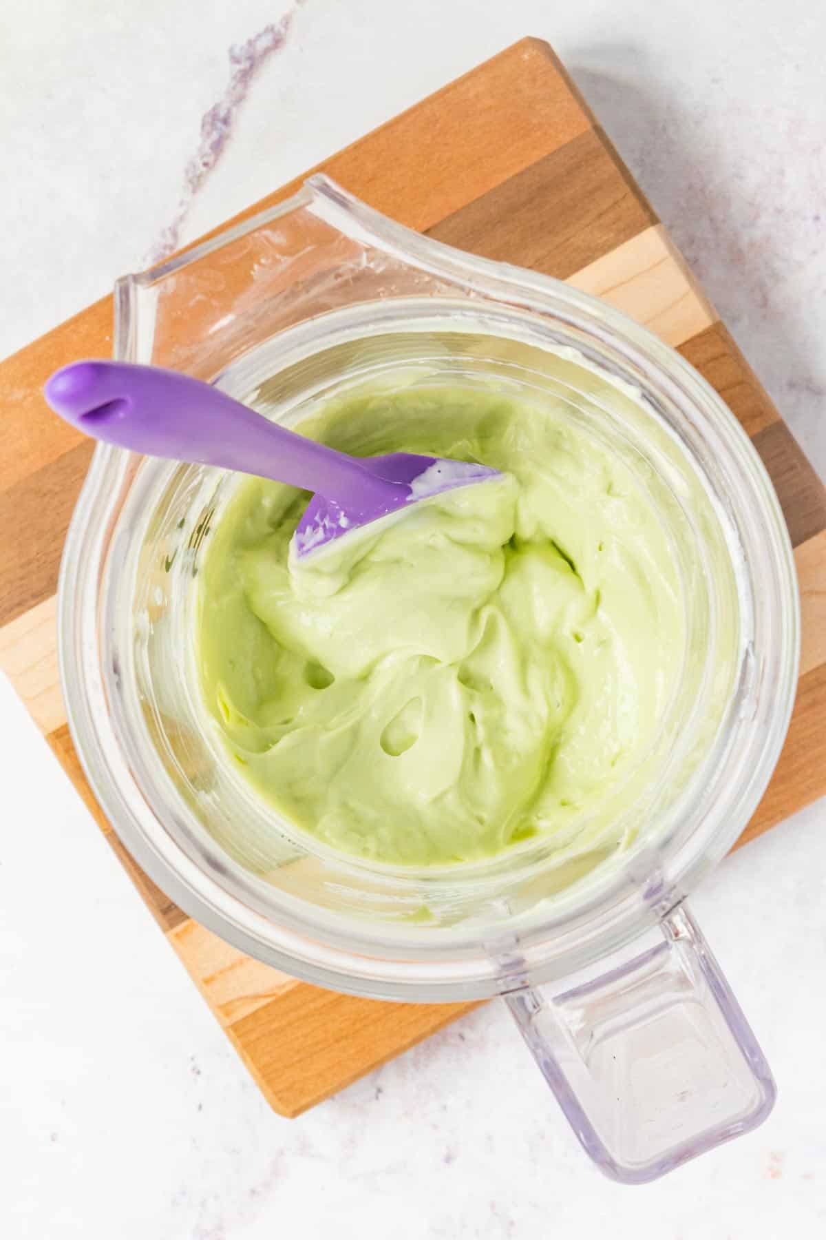 A spatula in the finished avocado crema in the blender jar.