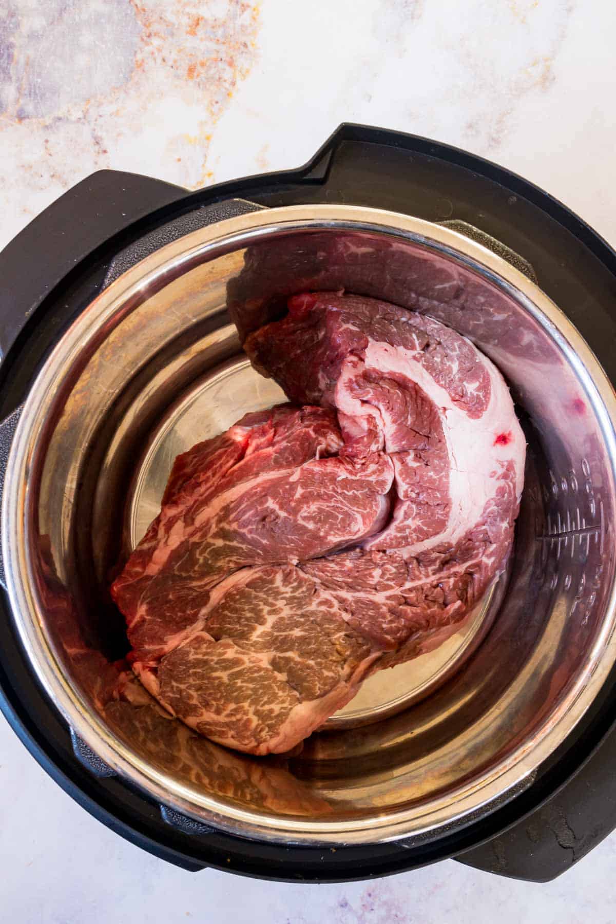 A chuck roast in the bowl of an Instant Pot.