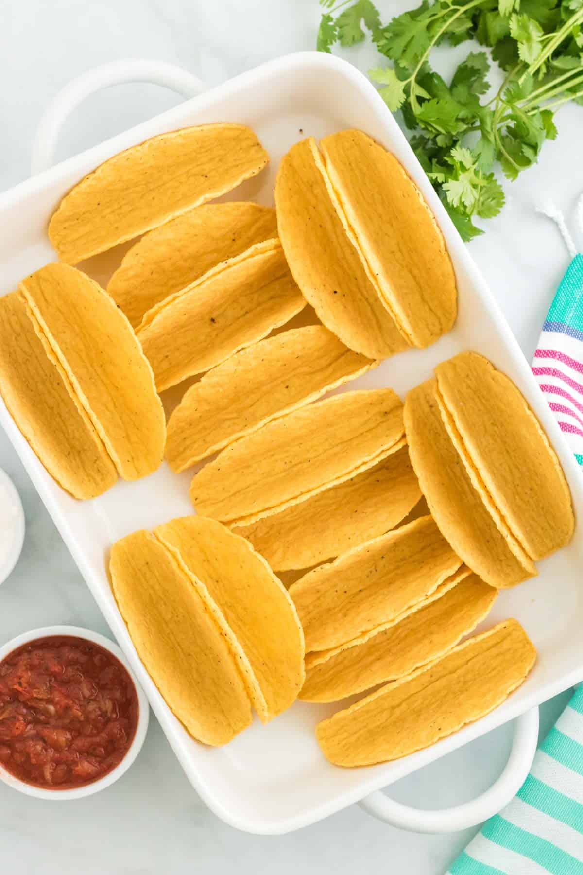 Empty hard taco shells in a white baking dish.