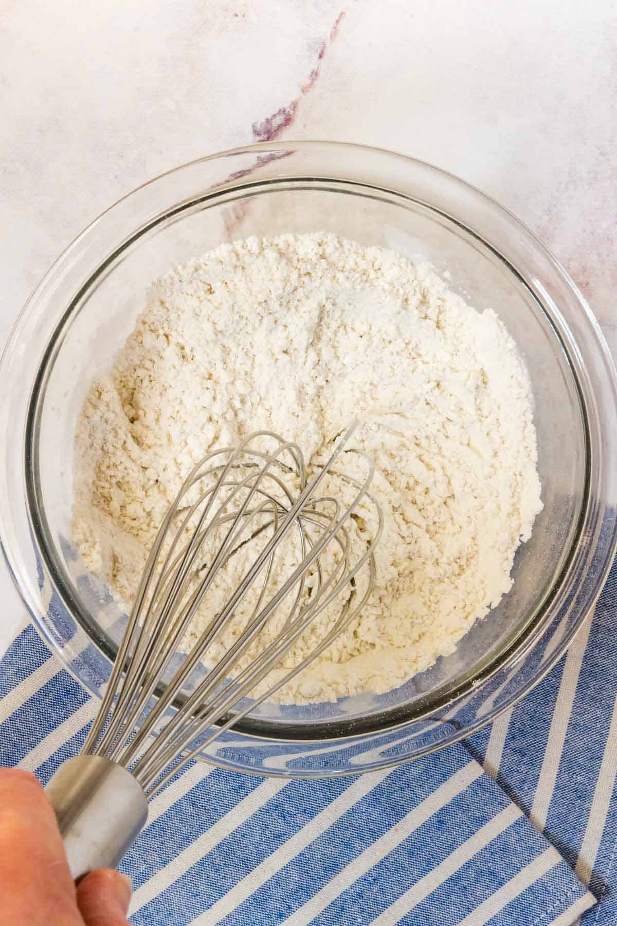 Dry pancake ingredients are whisked together in a glass mixing bowl.