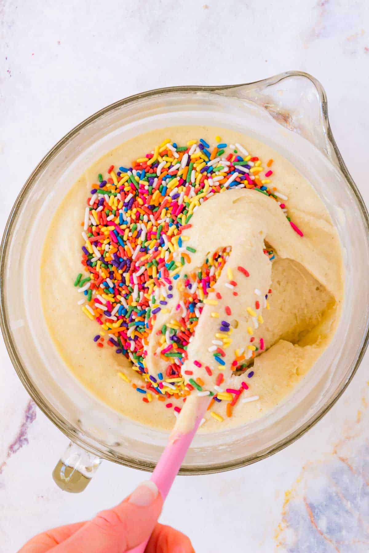 Rainbow sprinkles are folded into the gluten-free cake batter.