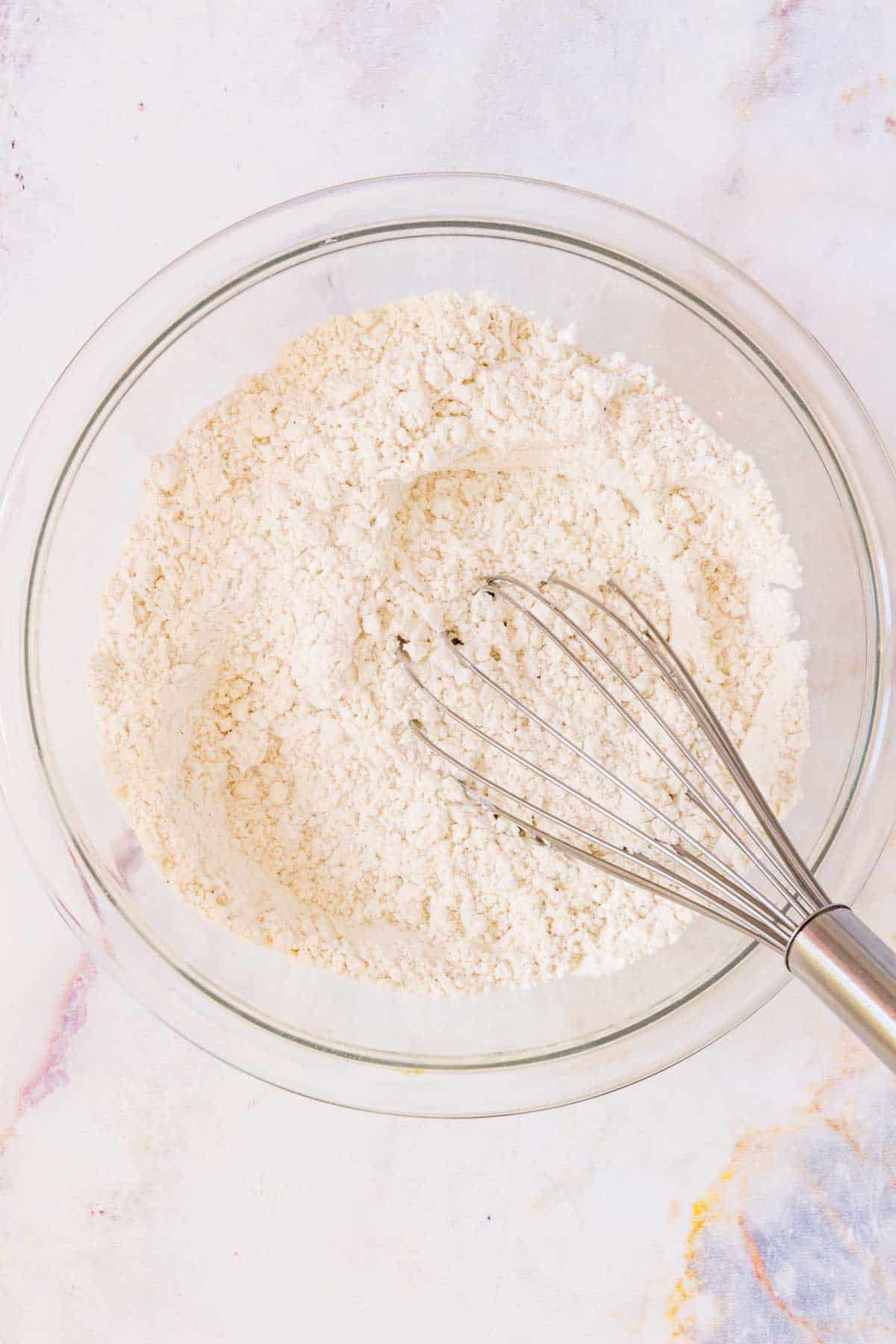 Gluten free flour and other dry ingredients are whisked together in a mixing bowl.