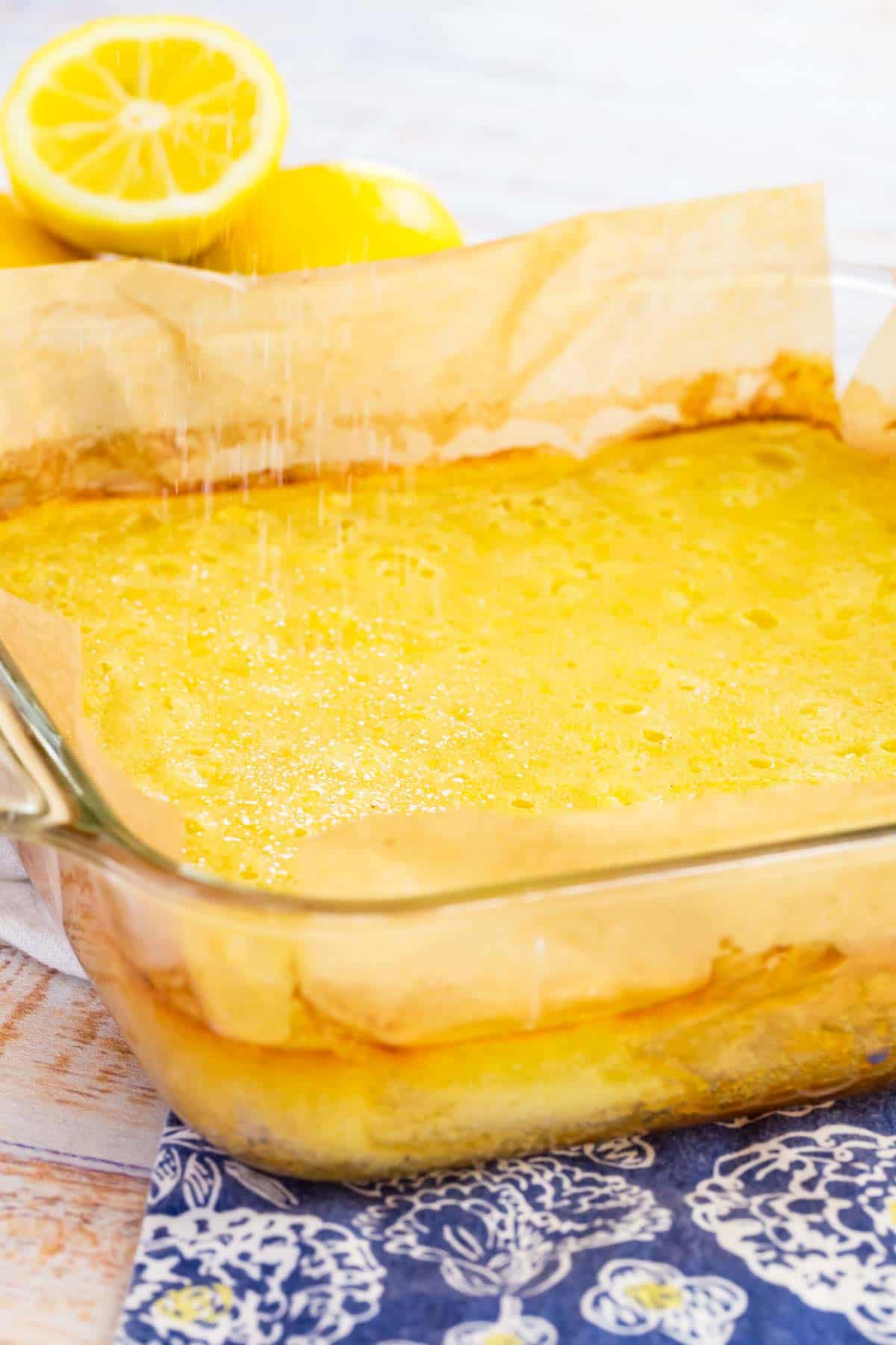 Baked gluten-free lemon bars in a glass baking dish lined with parchment paper.