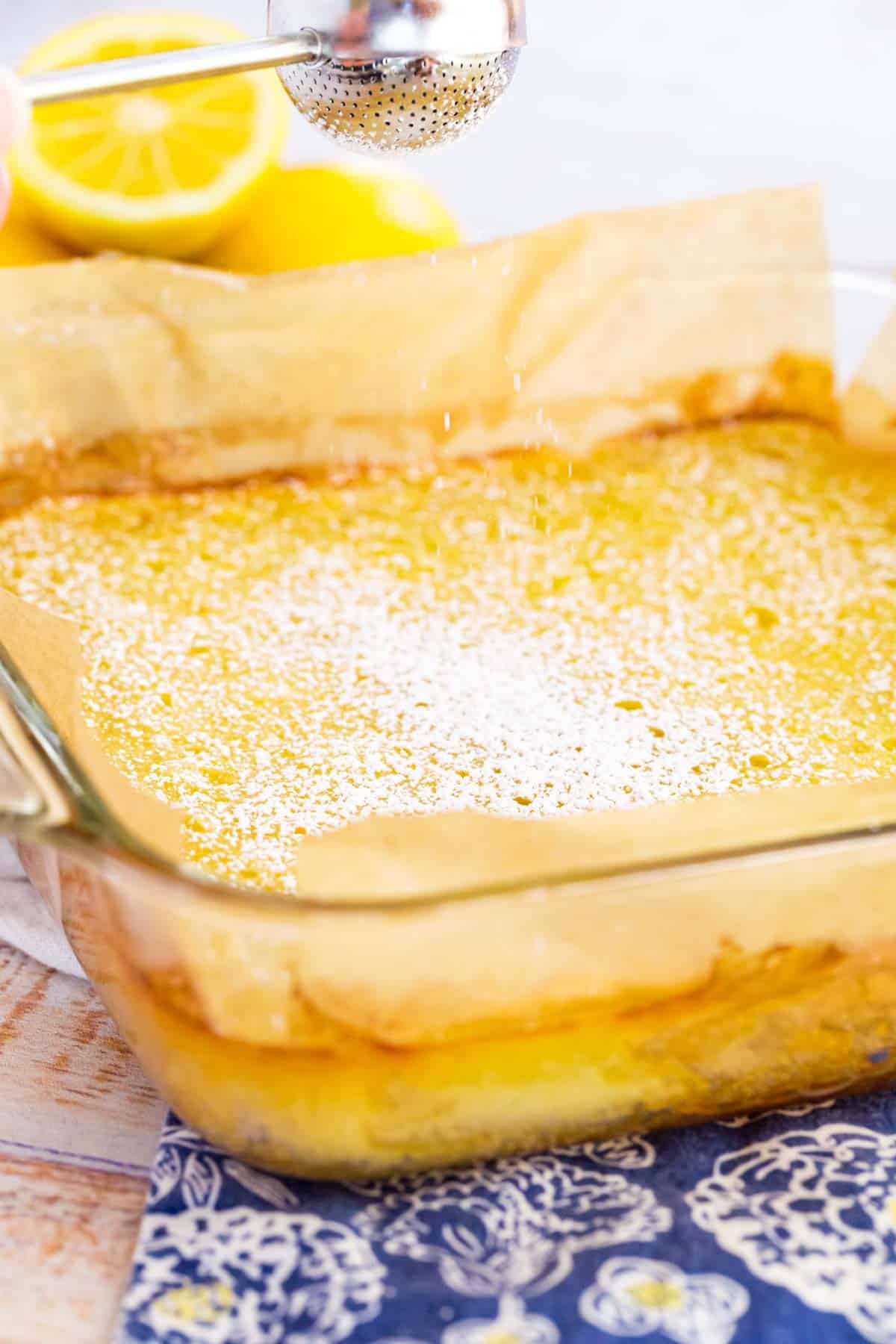 Powdered sugar is dusted over top a baking dish filled with gluten free lemon bars.