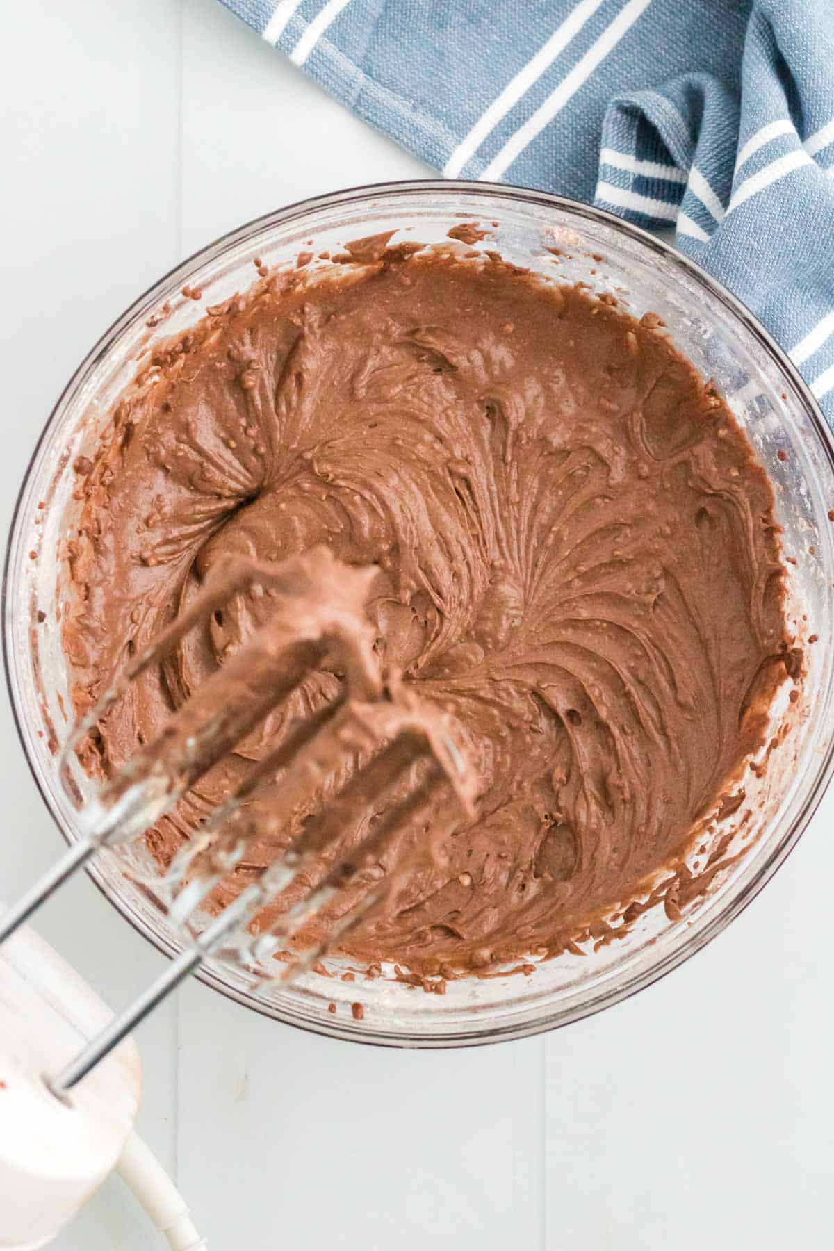 Beaters of a hand mixer of a bowl of the chocolate frosting.
