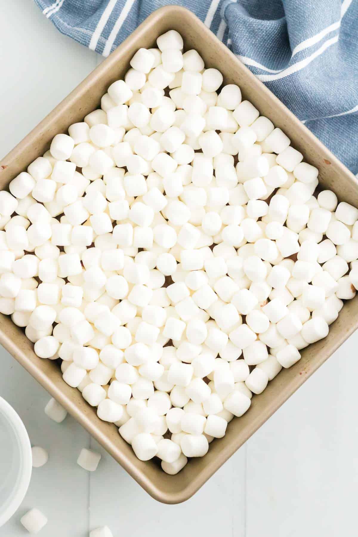 Mini marshmallows scattered on top of the pan of brownies.