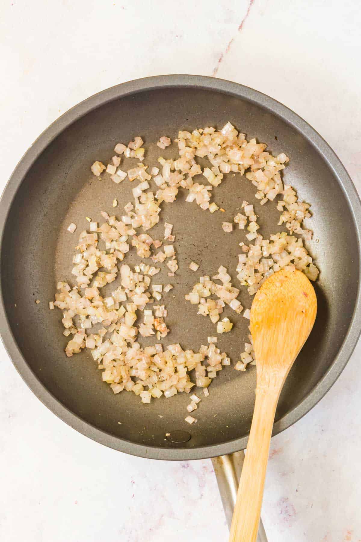 Minced shallot sauteeing in a small skillet.