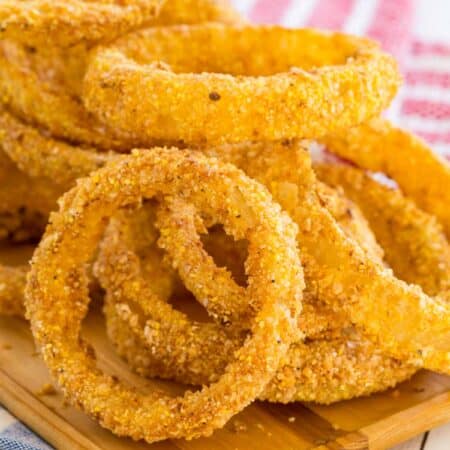 Crispy gluten free air fryer onion rings on a rectangular wooden serving tray.