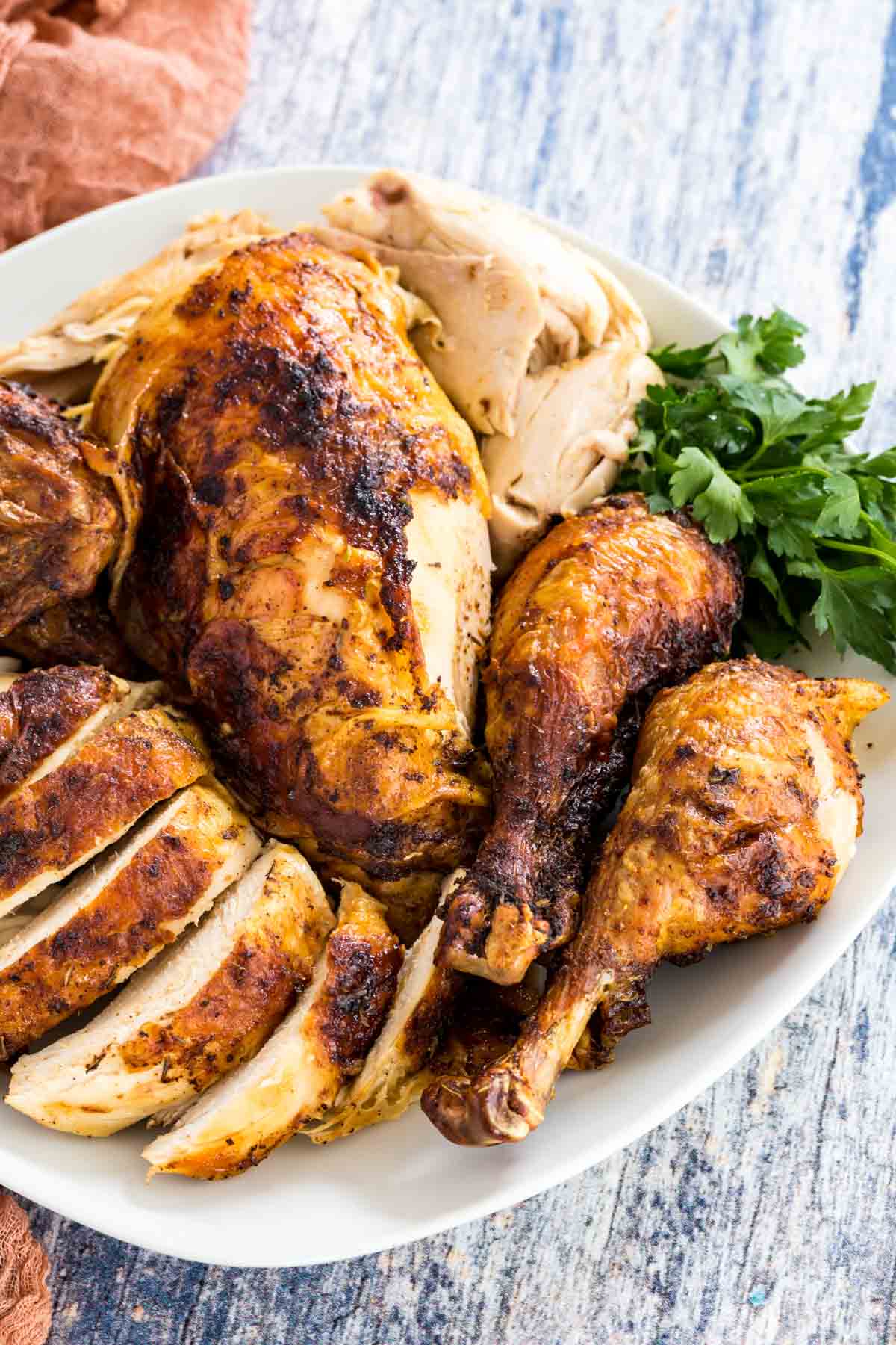 A plate of carved rotisserie chicken breasts, wings, and drumsticks.