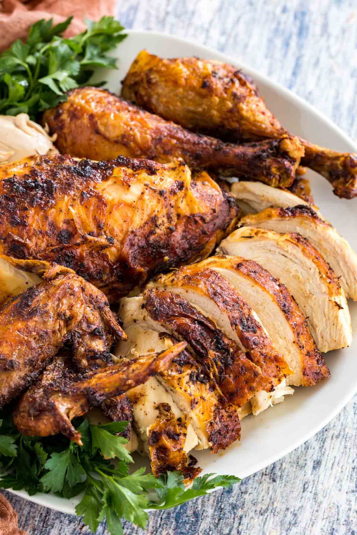 A plate of carved rotisserie chicken breasts, wings, and drumsticks.