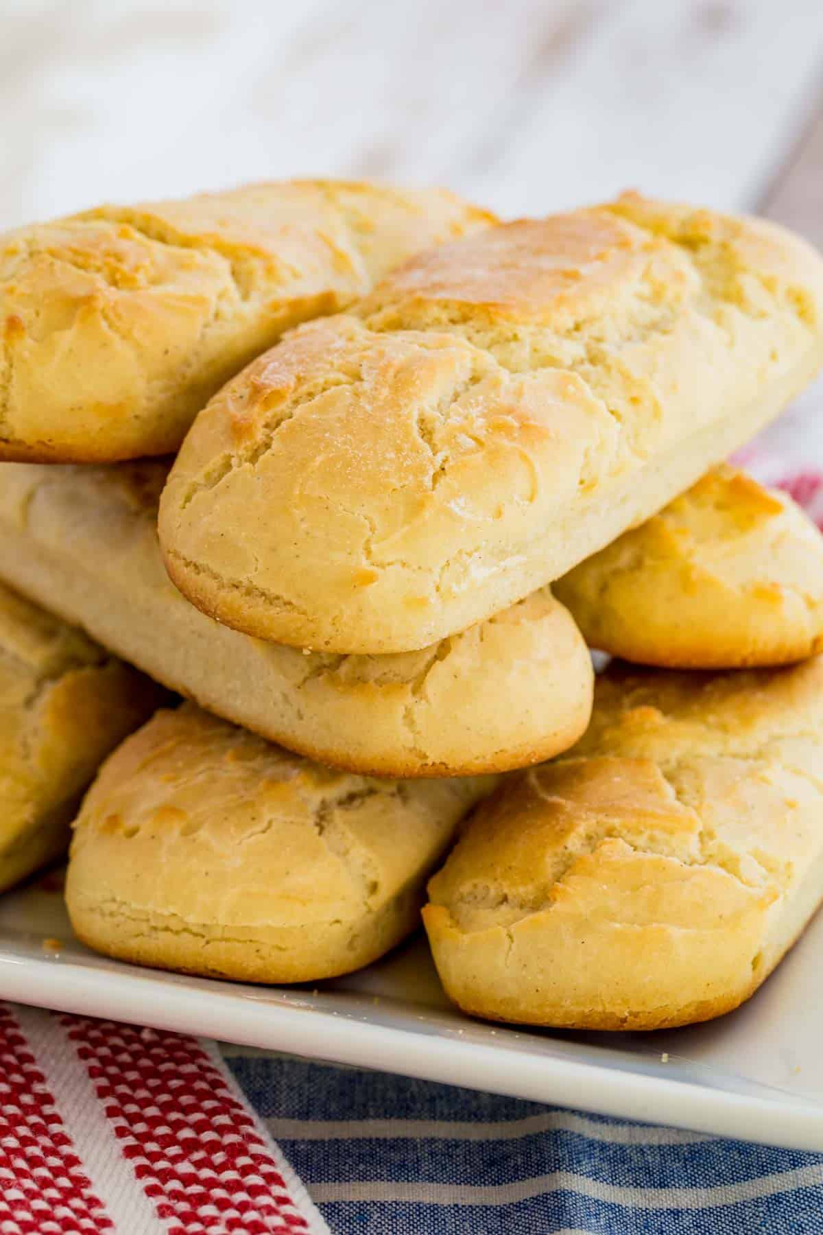 Gluten free hot dog buns stacked on a rectangular plate.