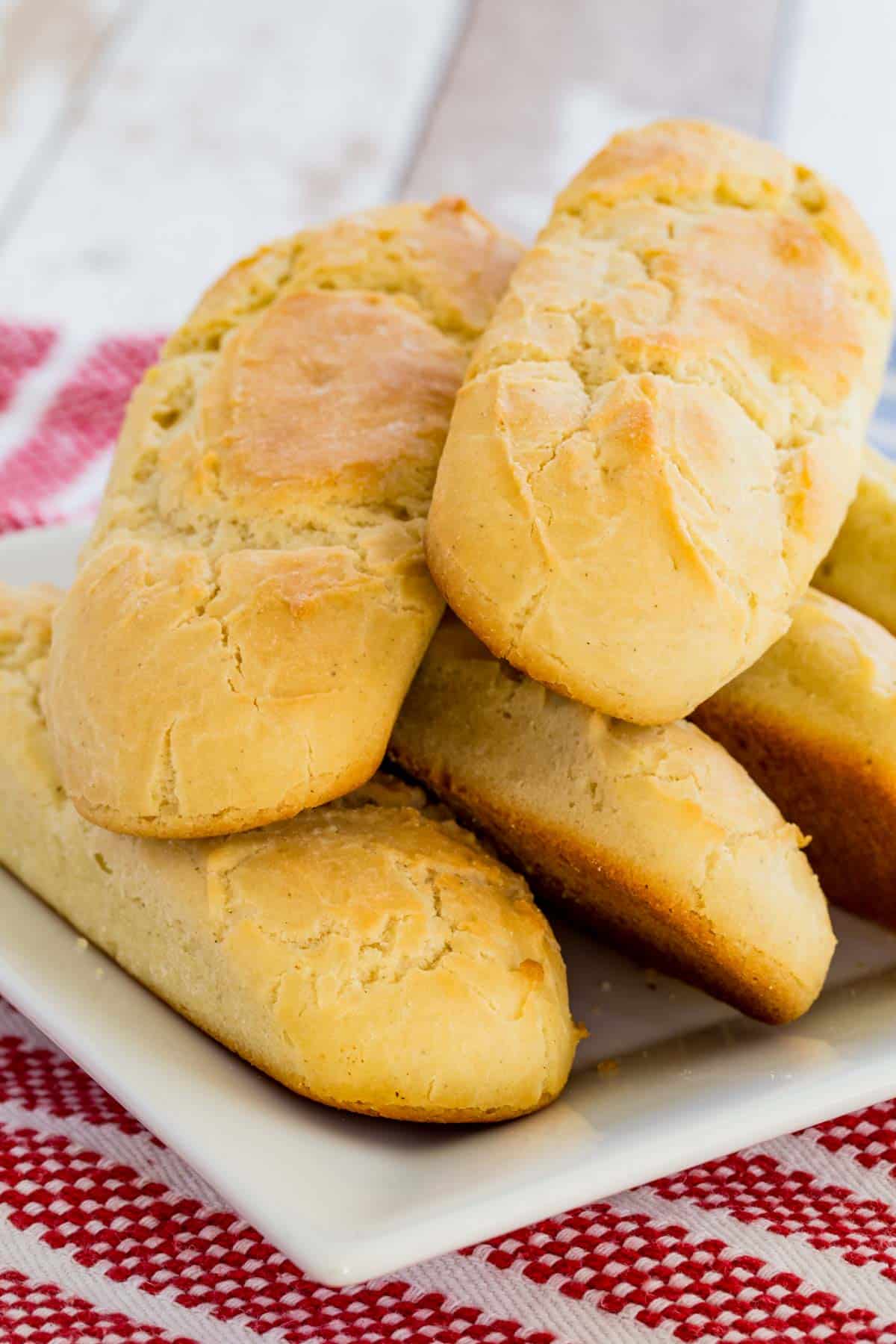 Gluten free hot dog buns stacked on a rectangular plate.