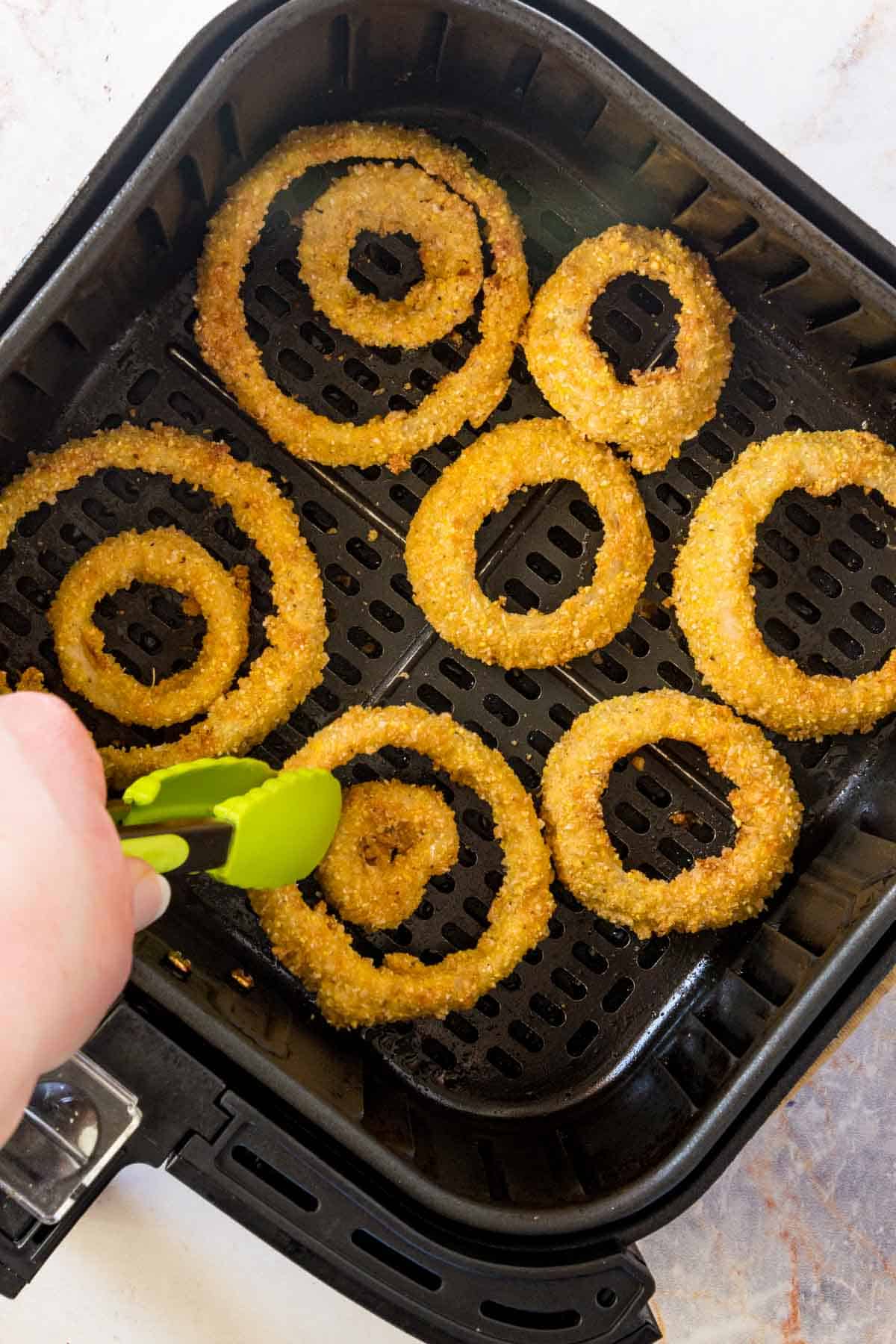Crispy onion rings cooking in an air fryer.