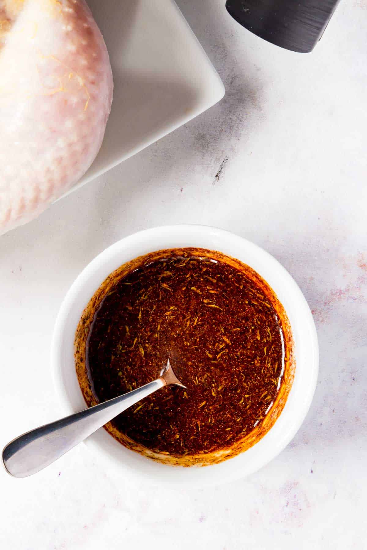 Chicken seasoning in a bowl next to a whole chicken.