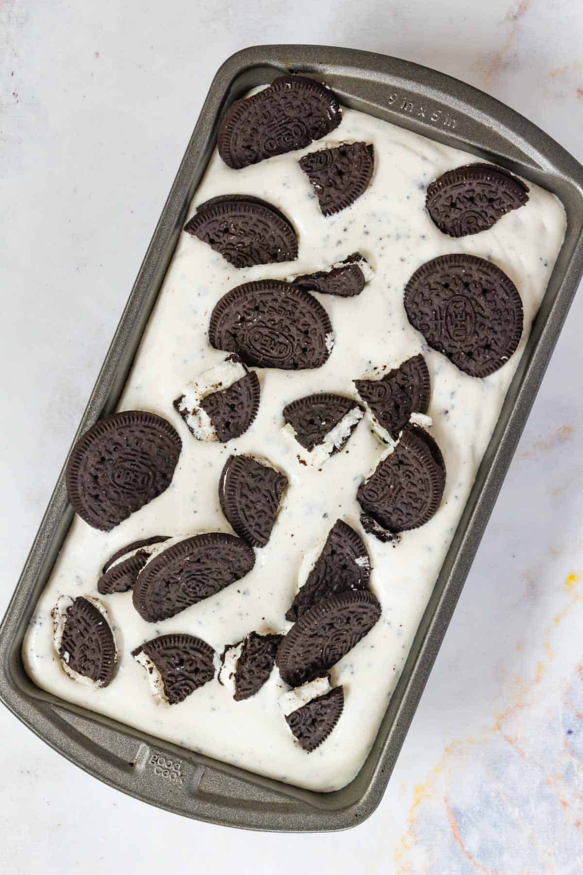 Cookies and cream ice cream topped with chocolate cookies, in a metal tub for freezing.