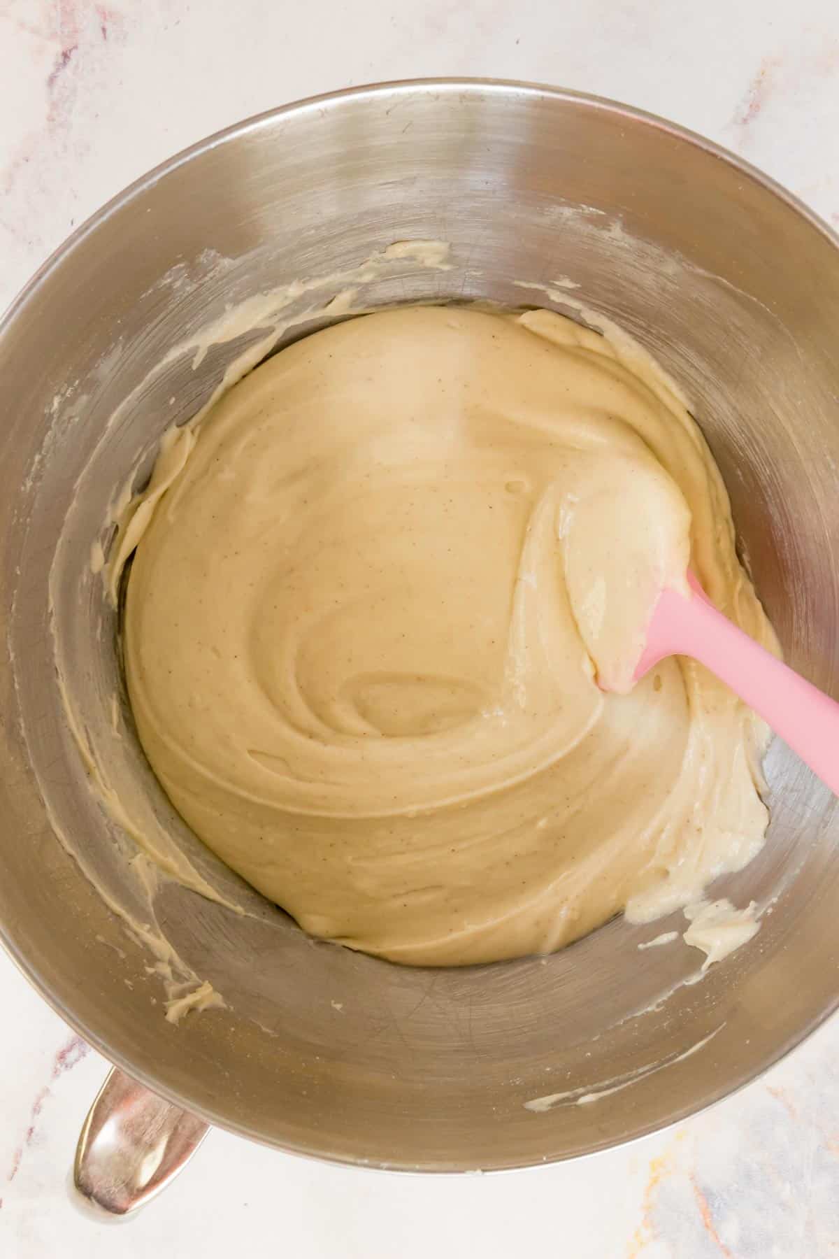 Gluten free hot dog dough is stirred together in a mixing bowl with a pink spoon.