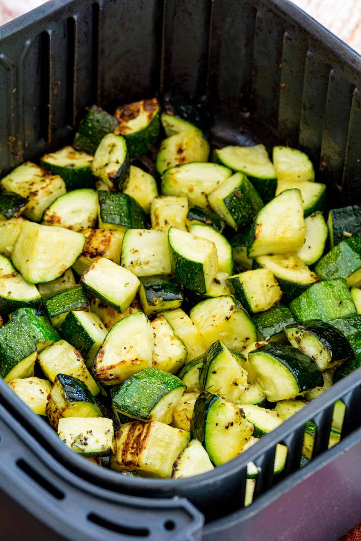 Roasted zucchini pieces inside the air fryer.