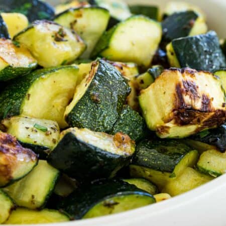 Close up of air fryer zucchini pieces in a white serving bowl.
