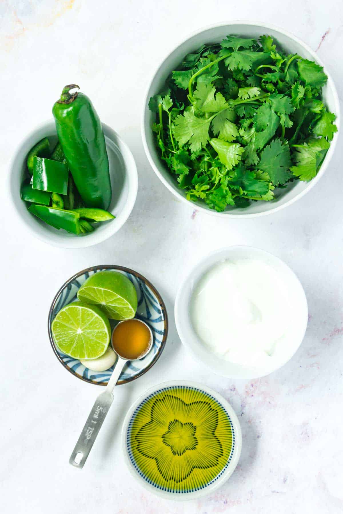 Ingredients to make Aji sauce in bowls on a marble countertop.