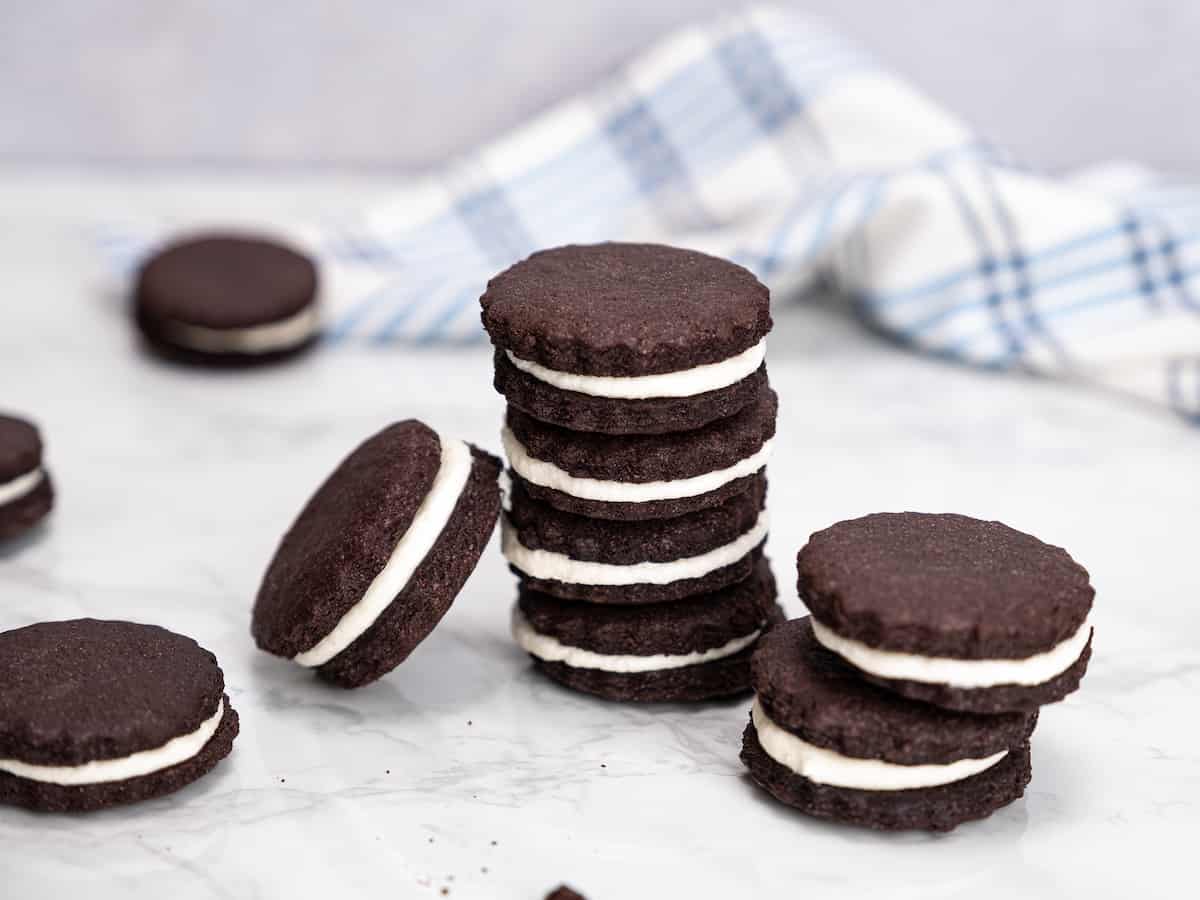 Gluten free Oreos stacked on top of one another on a white countertop.