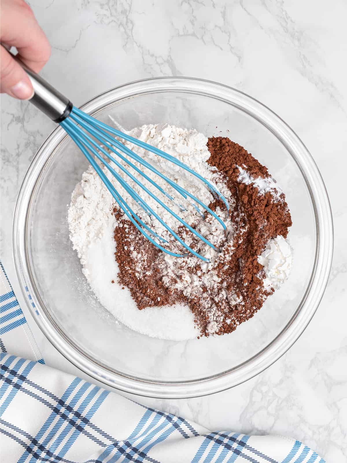The ingredients for chocolate cookies are whisked together in a mixing bowl.