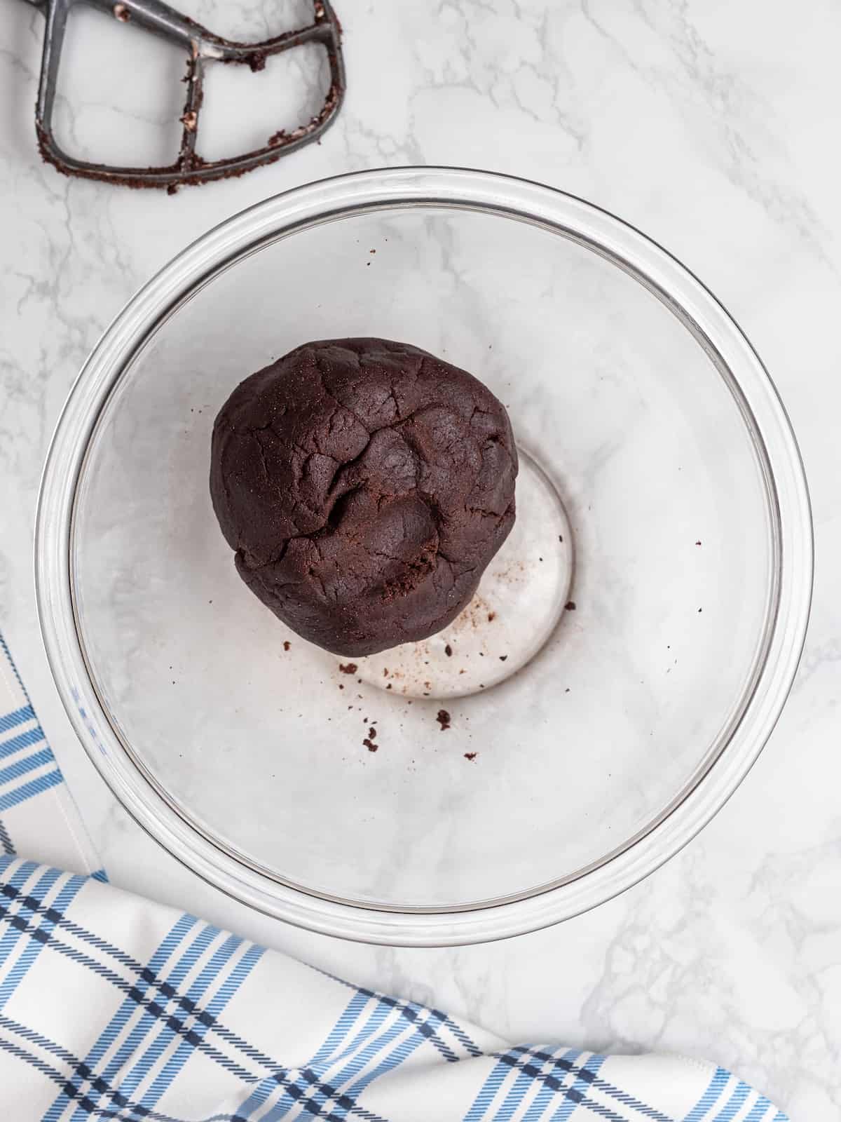 A chocolate dough ball in a glass mixing bowl.