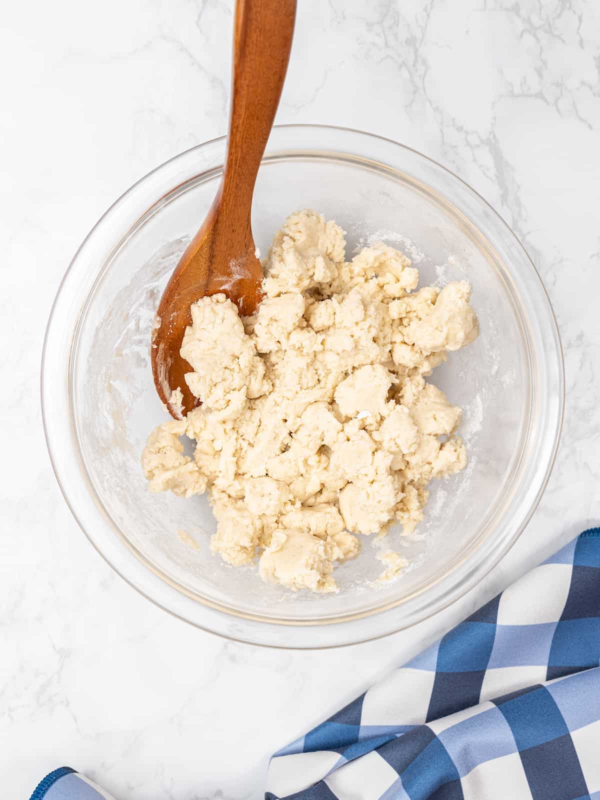 The dough topping comes together in a mixing bowl, with a wooden spoon.